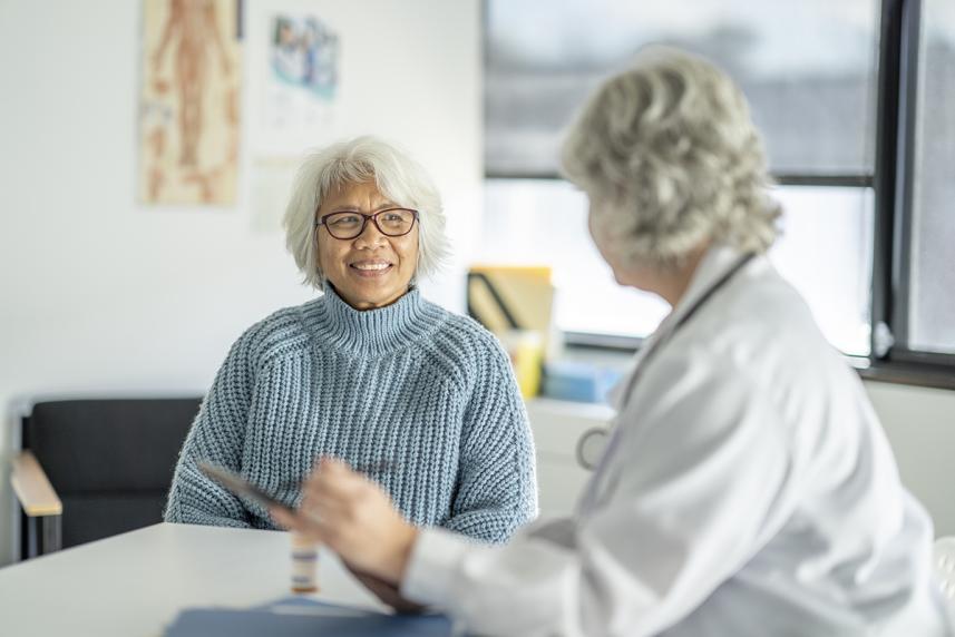 Doctor and smiling female patient talking in office
