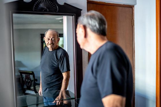 older man looking in a mirror thinking about colon cancer screening